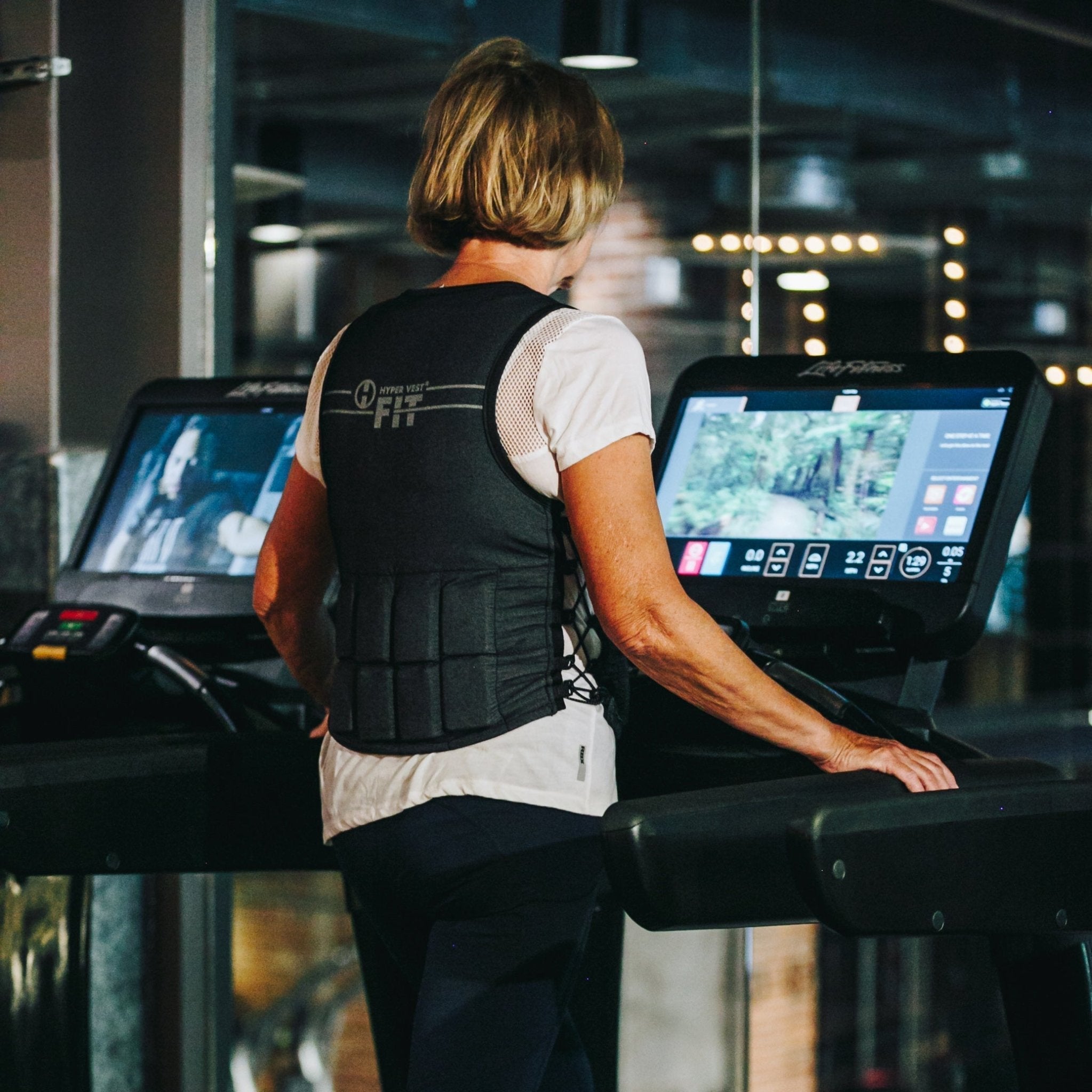 image of a woman walking on a treadmill in a health club wearing a weighted vest for women