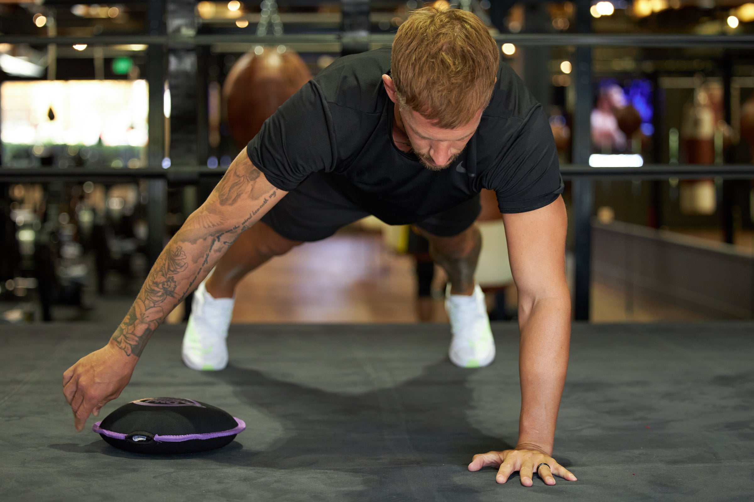 image of a male athlete model doing a plank and using a Hyperwear SandBell for a pull through exercise in a gym