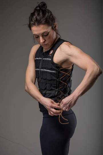 Picture of a female fitness model adjusting the side lacing on her black hyper vest elite gravity sportswear vest