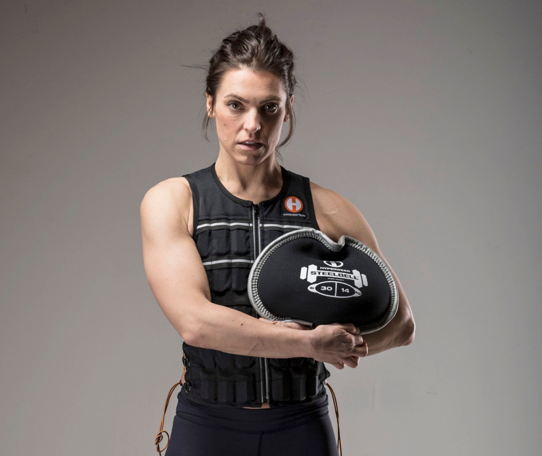 image of female fitness model in a weighted vest holding a SteelBell medicine ball slam alternative free weight