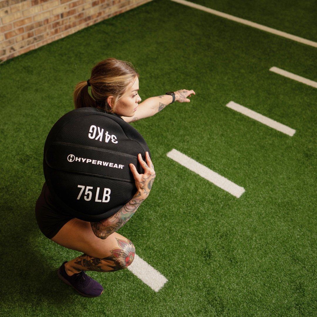 Image of a female fitness model doing a shoulder squat with aHyperwear Neoprene Strongman Sandbags