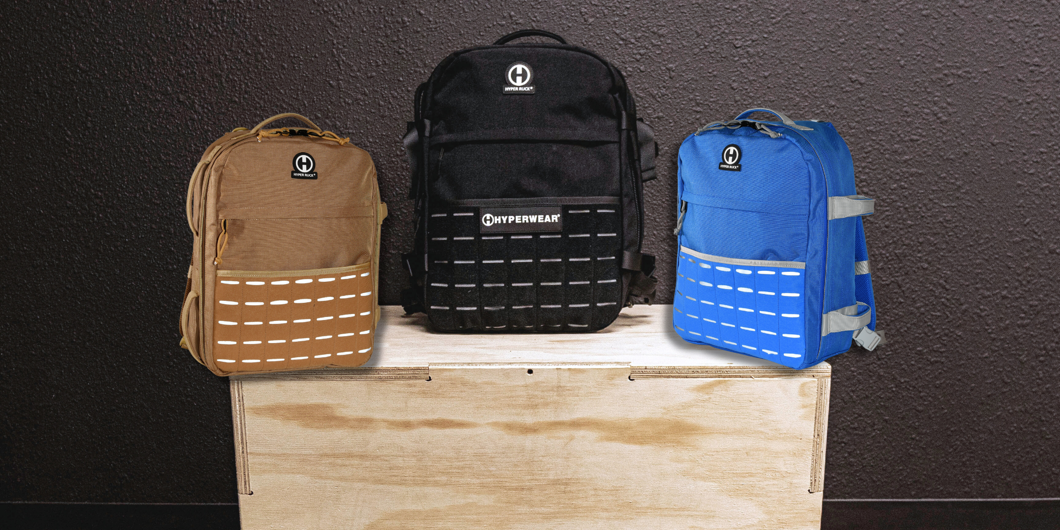 product image of the coyote brown, black and blue hyper ruck rucking backpacks displayed on a wood plyo box