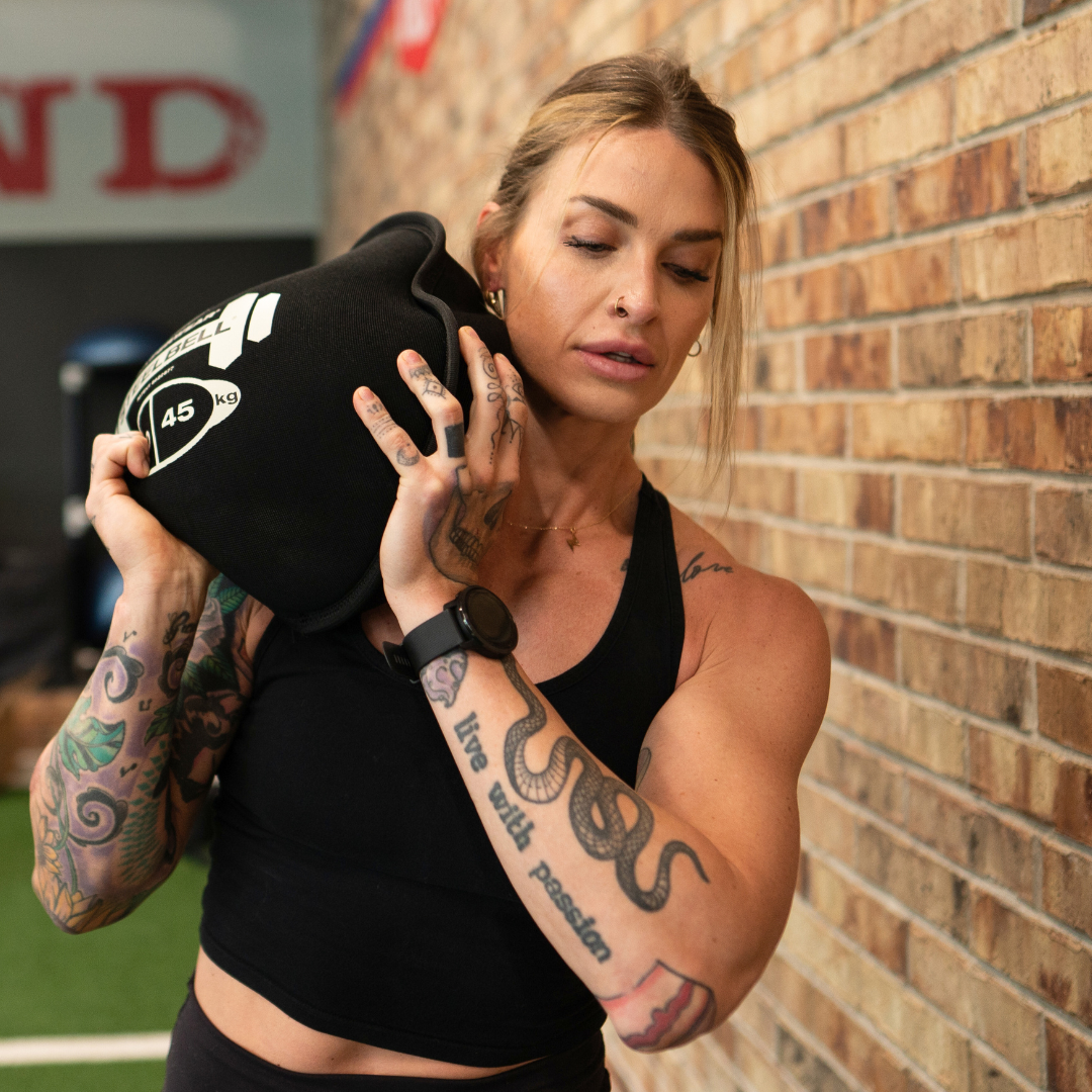 picture of an athlete shouldering a heavy steelbell slam ball inside a gym