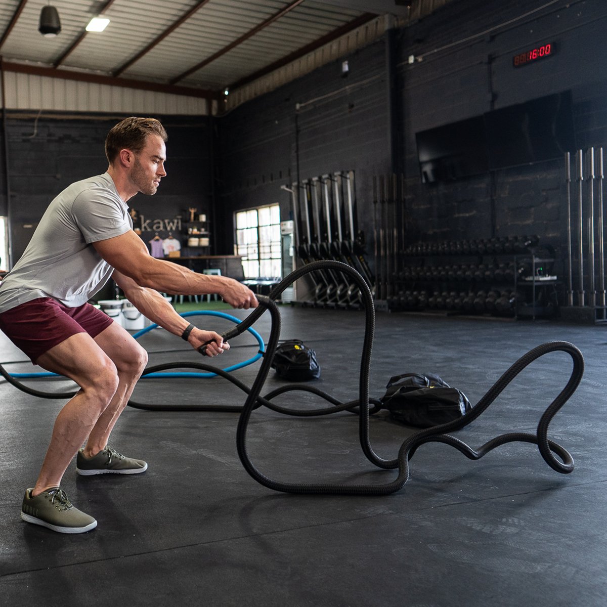 A group is pictured in a crossfit or garage gym using a hyper rope weighted battle rope in a small space