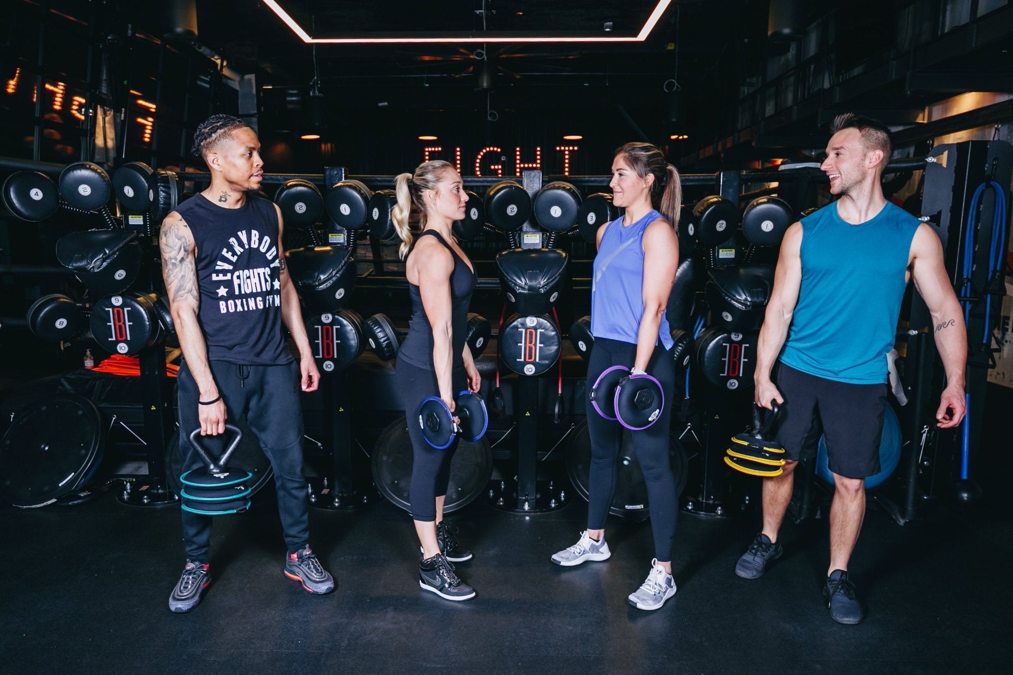 Picture of a group of four fitness models in a boxing gym holding hyperwear softbell kettlebells and dumbbells