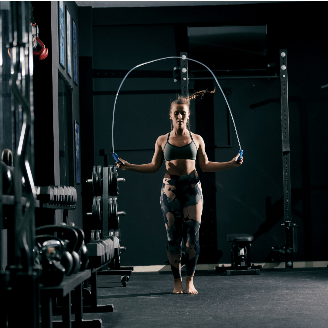 a female CrossFit athlete is pictured inside a box gym jumping rope with a speed rope