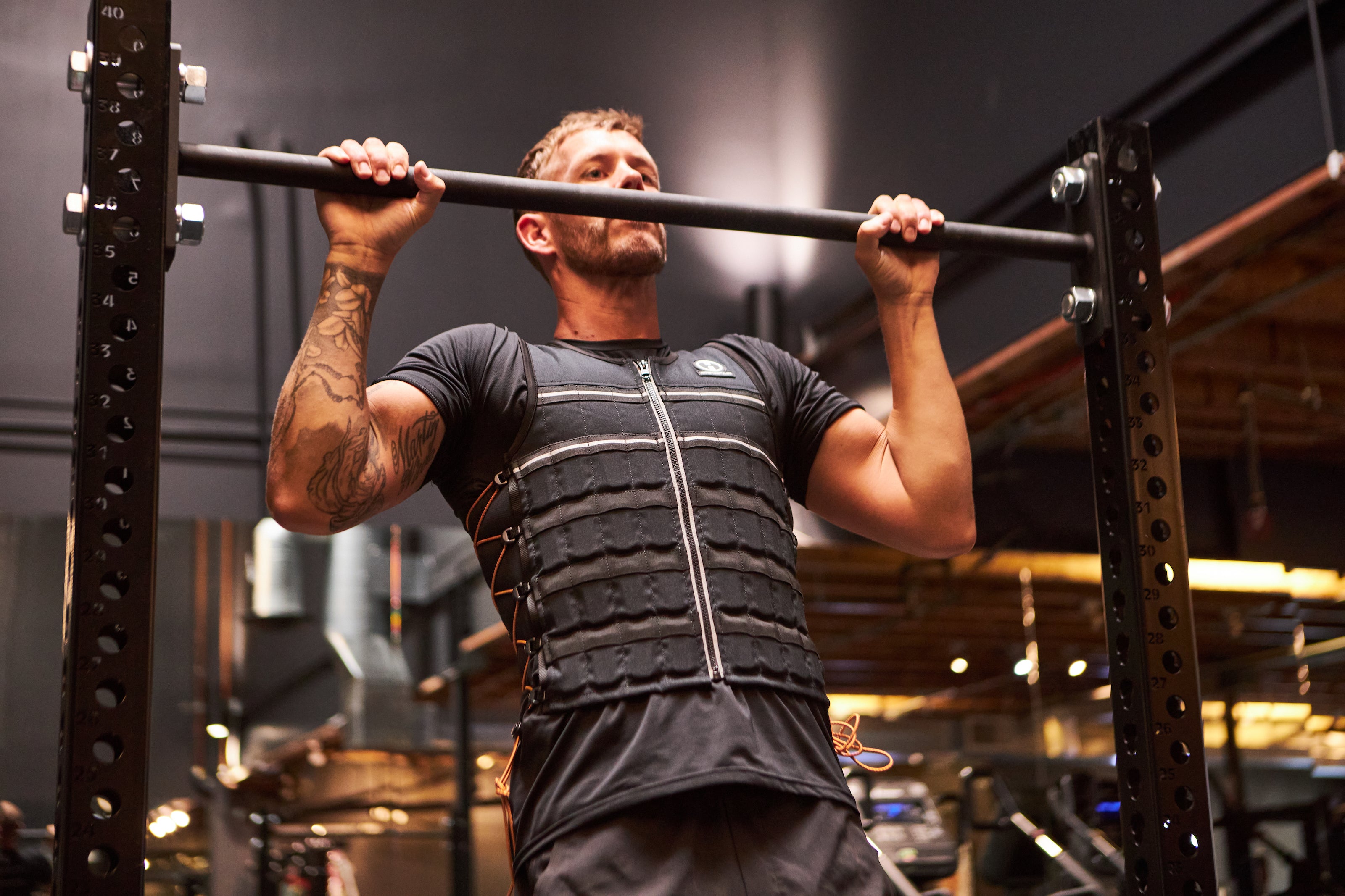 image of male fitness model doing a pull up while wearing black hyper vest elite weight vest