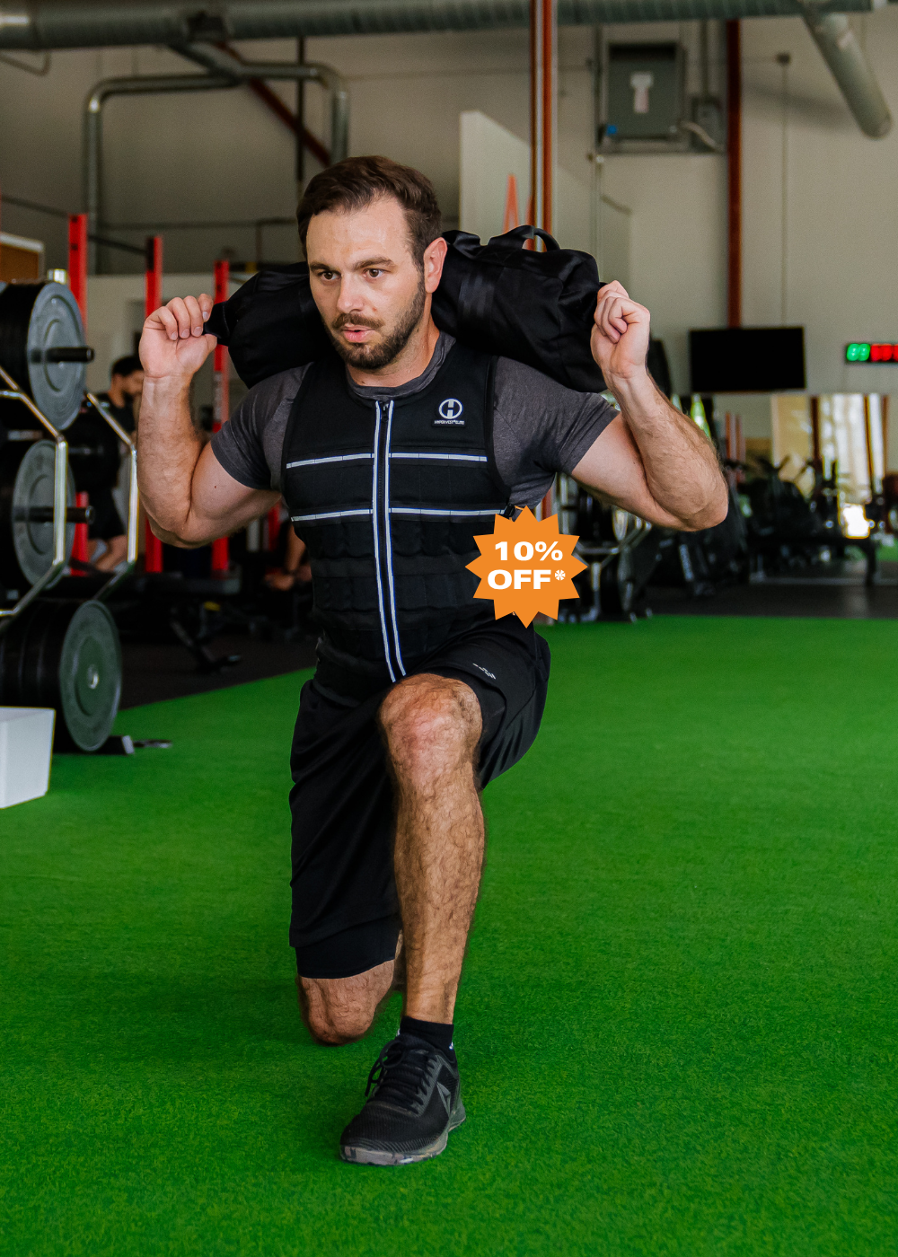 picture of an athlete facing the camera lunging with a Hyperwear Hybrid Race™ 10KG sandbag training for the Hyrox sandbag lunge