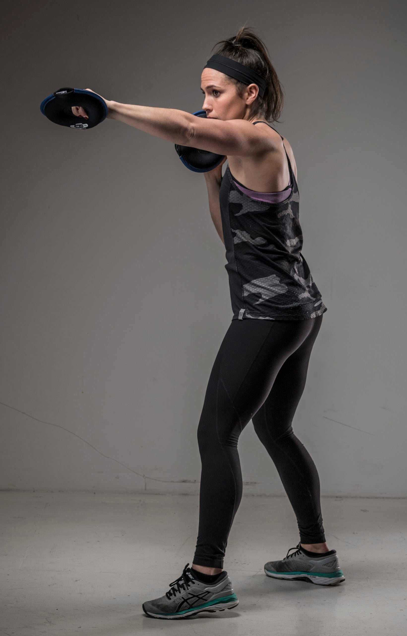 A female fitness model is pictured holding a softbell hand weight plate in each hand doing weighted punches