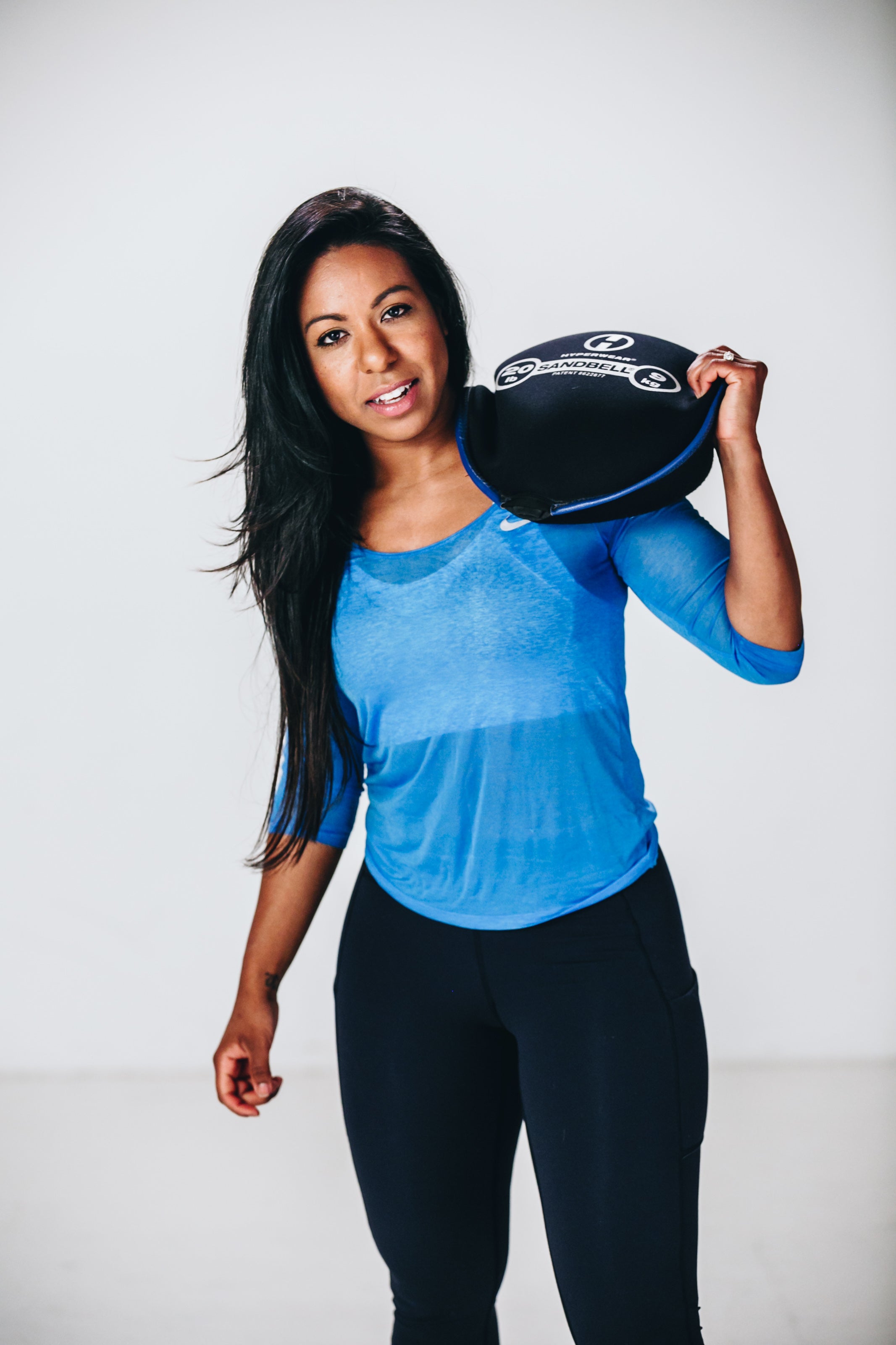 image of female fitness model holding sandbell sandbag training weight on her shoulder