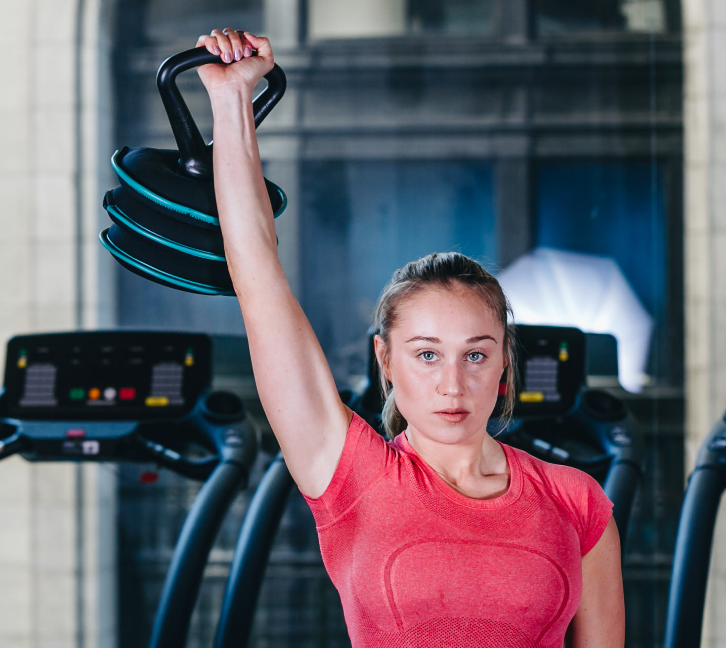 picture of a female fitness model doing a kettlebell single arm press with a softbell adjustable soft kettlebell