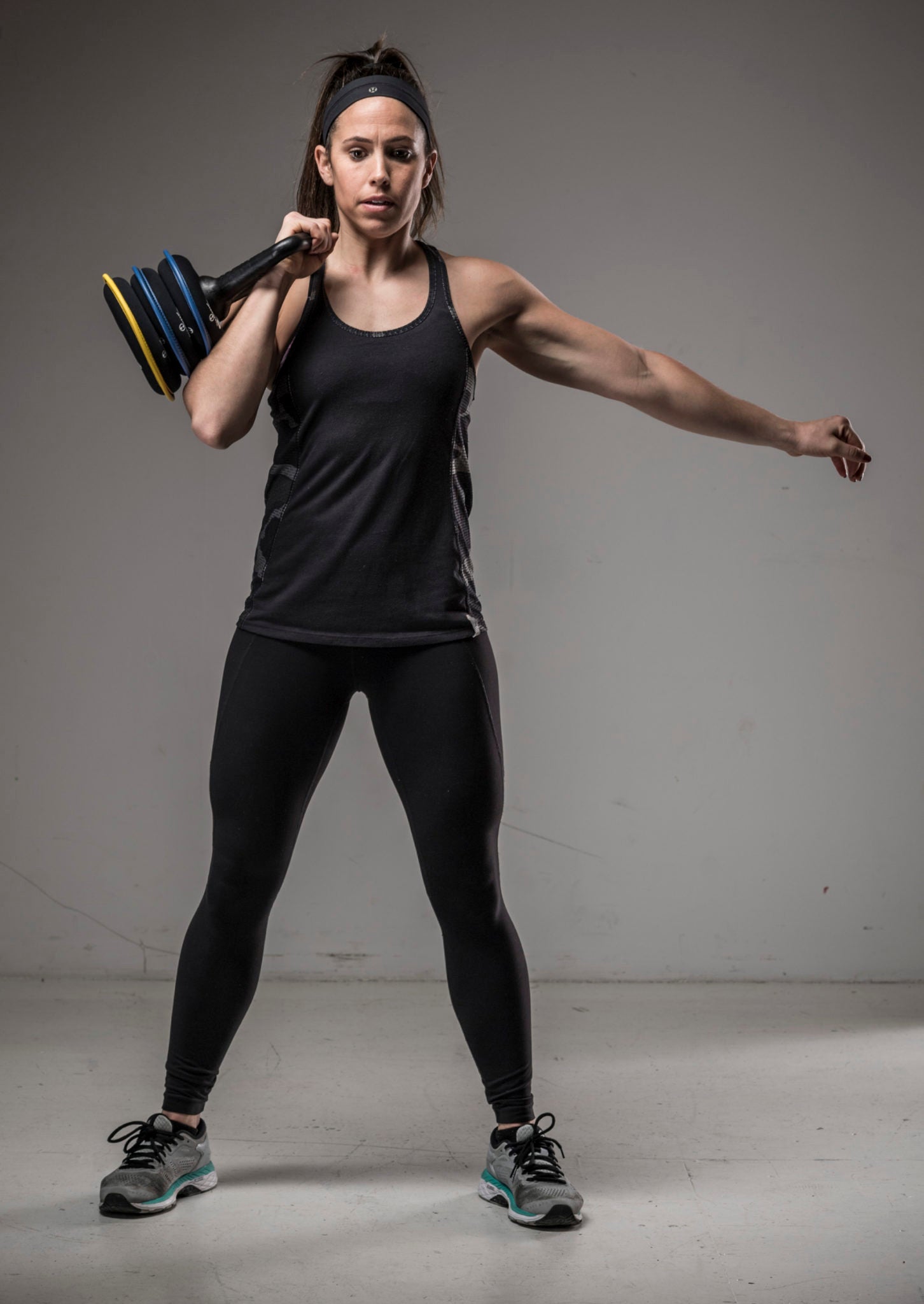 picture of a female fitness model holding a SoftBell soft kettlebell against her shoulder preparing to press overhead