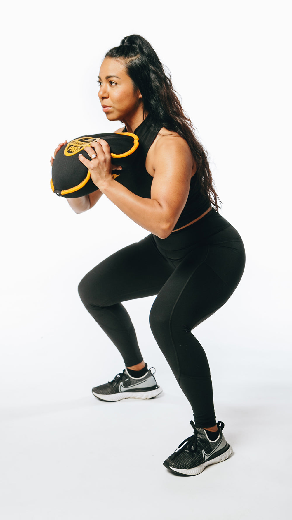picture of a female fitness model doing sandbag loaded front squat exercise for functional strength
