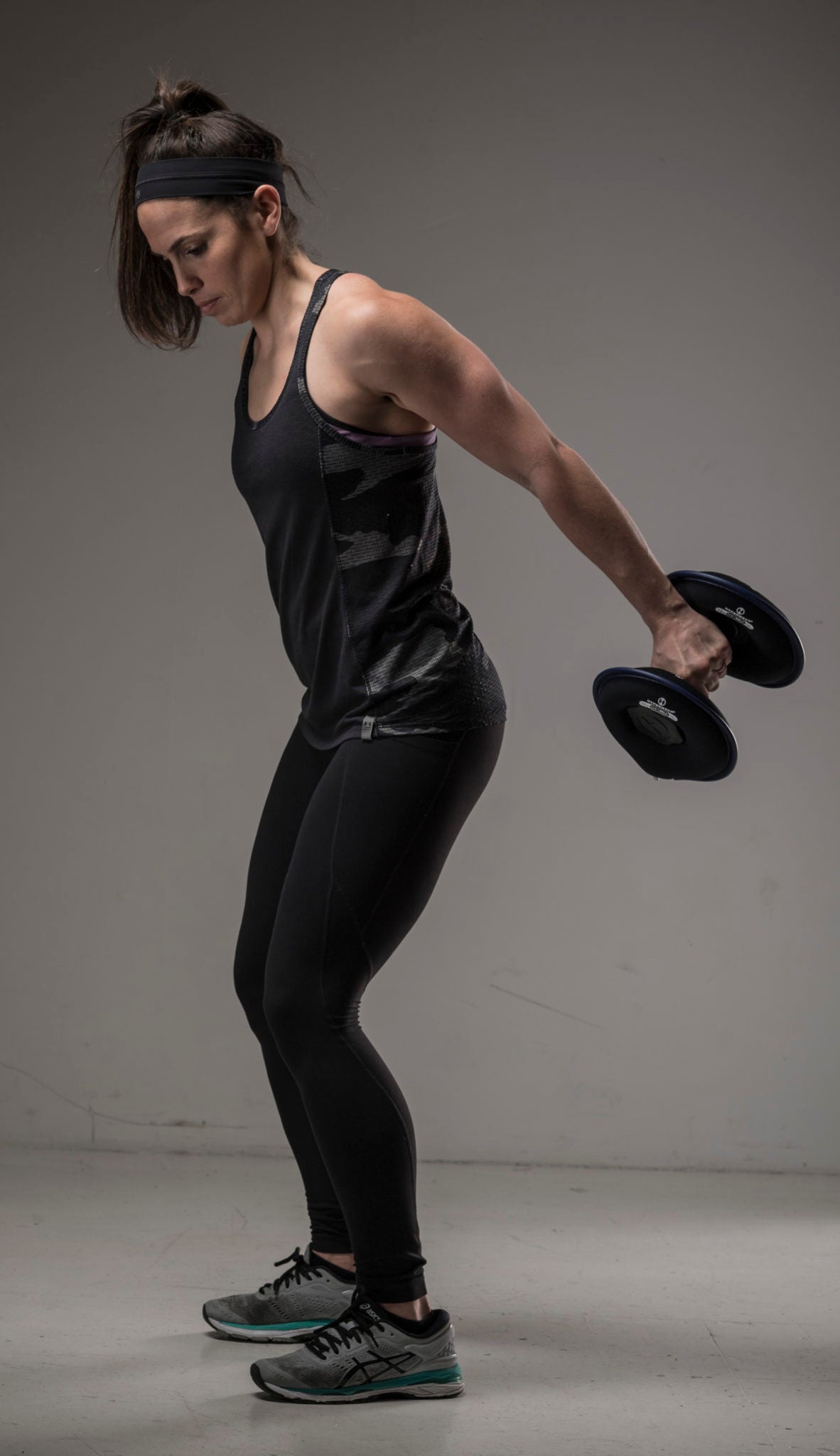 Image of female fitness model standing doing a back tricep extension with an adjustable dumbbell from Hyperwear
