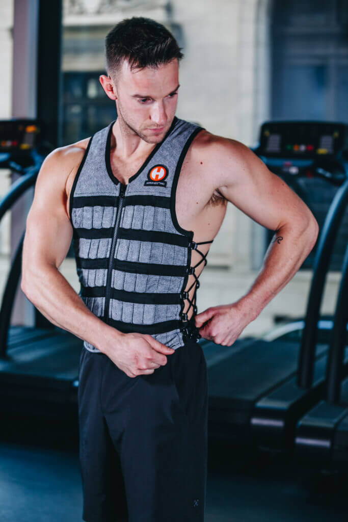 picture of a male fitness model adjusting the fit of a hyper vest pro weight vest by cinching the side cords