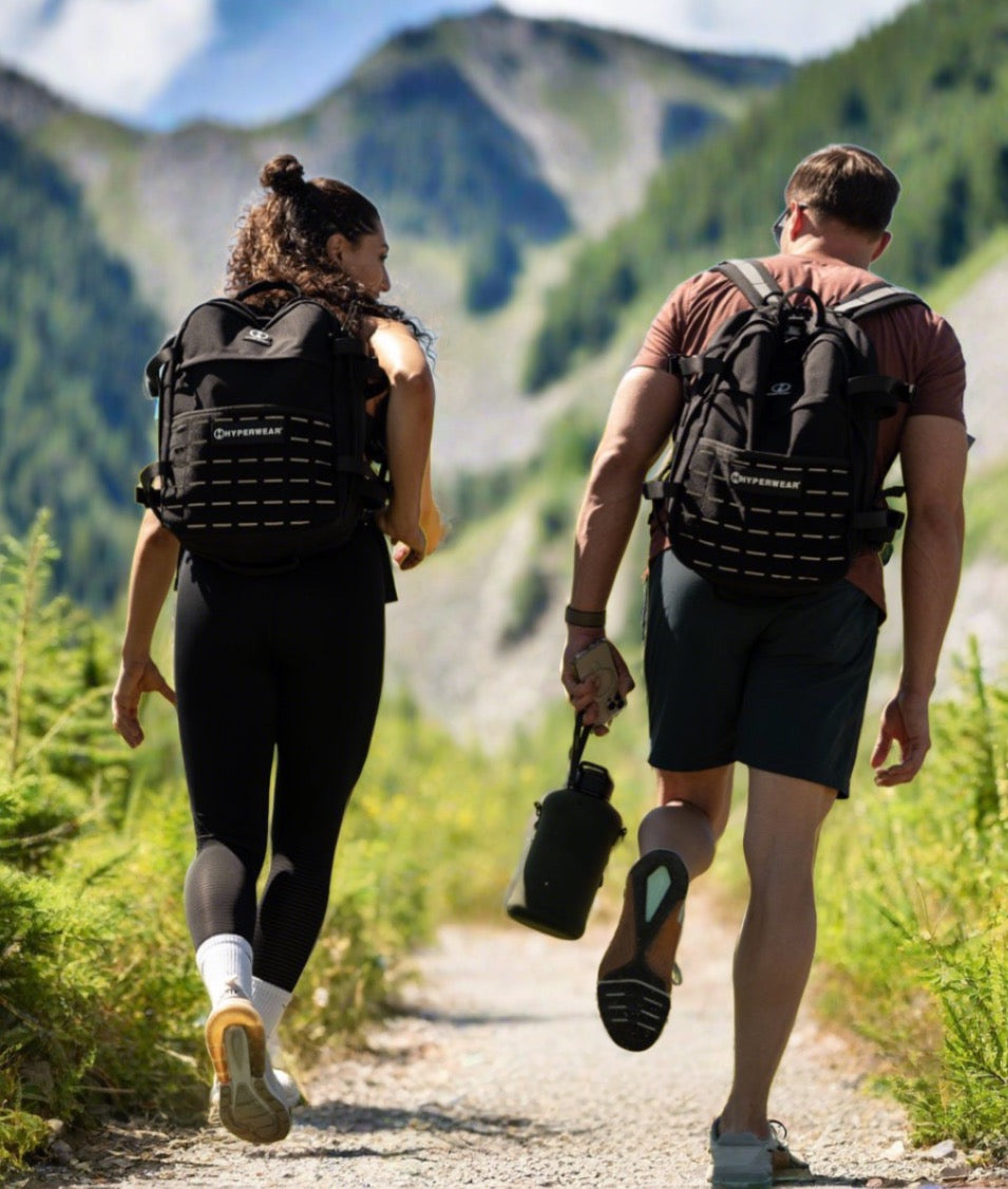 A couple is pictured rucking on a wooded trail using Hyper Ruck rucking backpacks